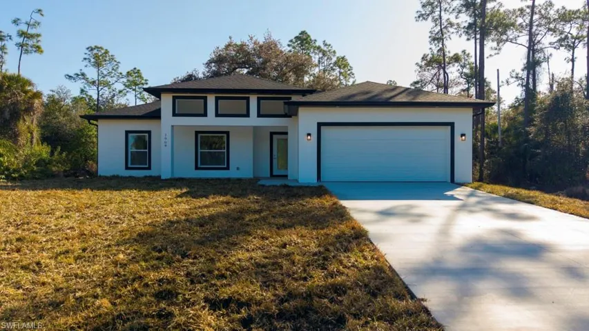 Prairie-style house featuring a garage, driveway, a front lawn, and stucco siding