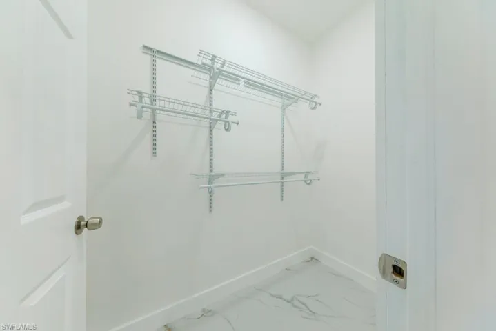 Laundry room featuring baseboards and light marble finish flooring