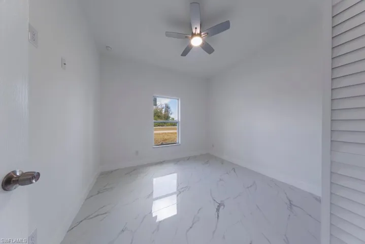Unfurnished room with light marble finish floors and a ceiling fan