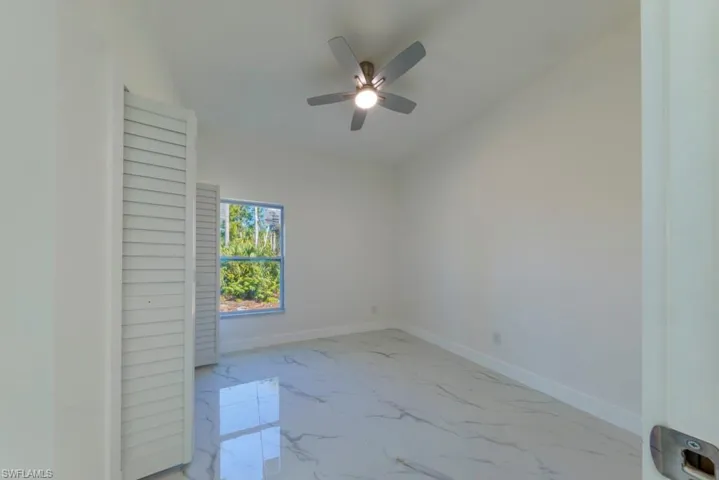 Unfurnished room featuring light marble finish flooring and a ceiling fan