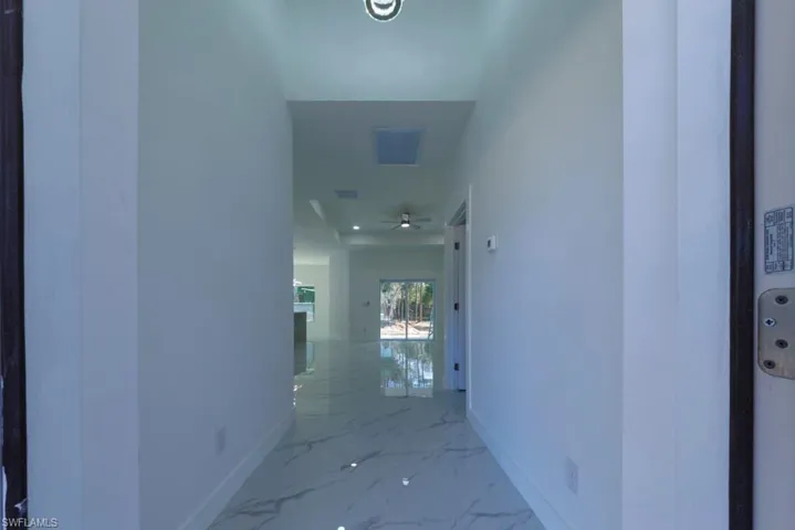 Hallway featuring baseboards and marble finish floors