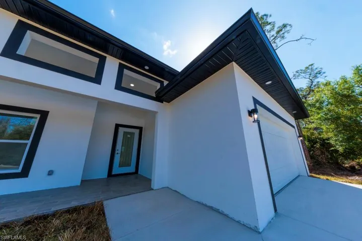 View of exterior entry featuring stucco siding, a garage, and concrete driveway