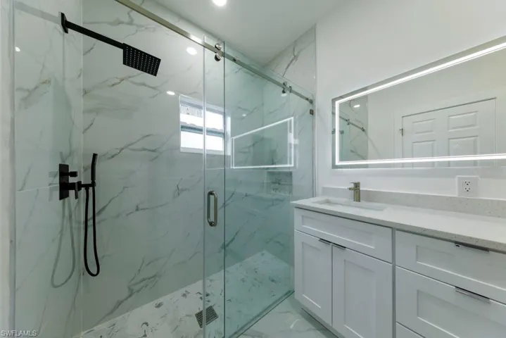 Bathroom with vanity and a marble finish shower