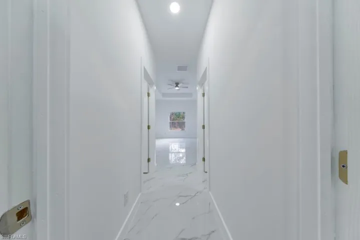 Hallway with marble tiled flooring and recessed lighting
