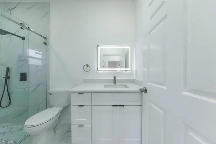 Bathroom featuring vanity and a marble finish shower