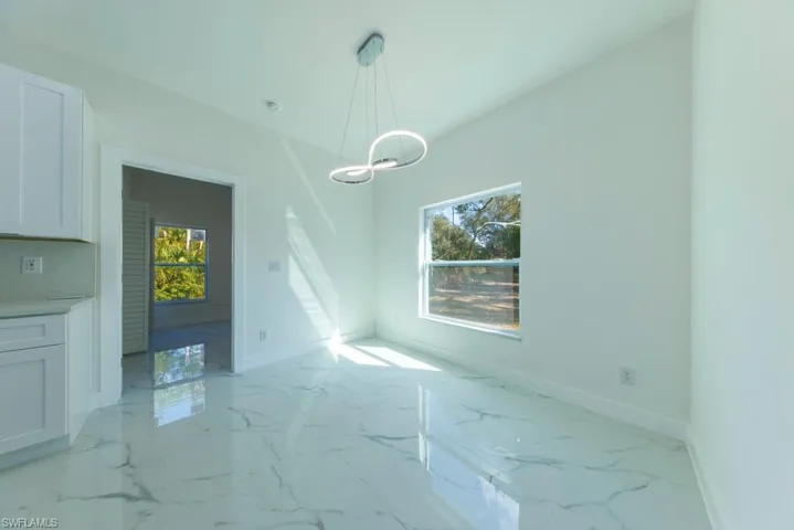 Unfurnished dining area featuring light marble finish flooring, plenty of natural light, and hanging lights