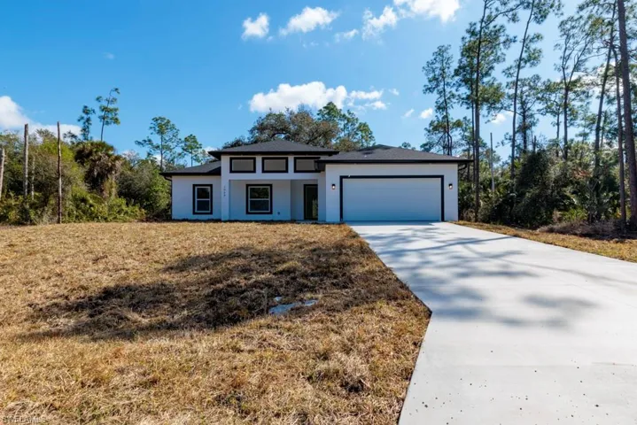 View of front of property featuring driveway, a garage, stucco siding, and a front yard