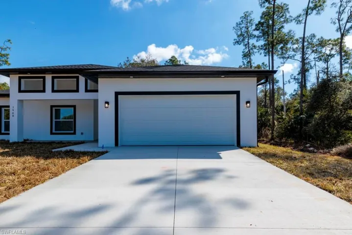 Prairie-style home with stucco siding, driveway, a garage, and roof with shingles