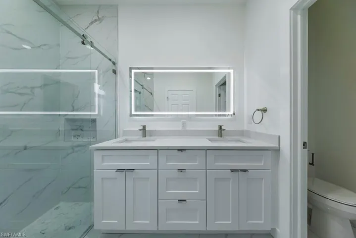 Bathroom with double vanity and a marble finish shower
