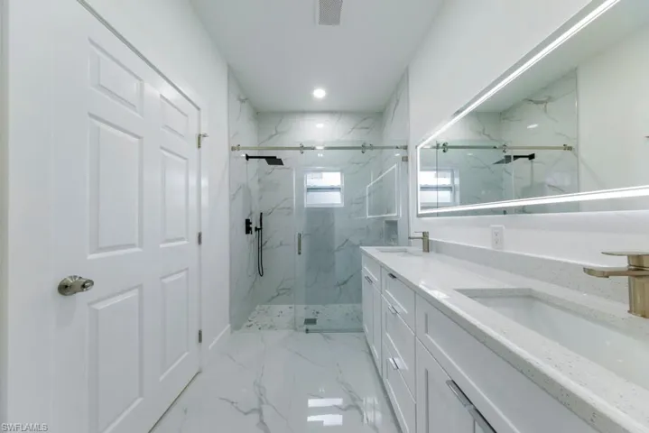 Full bathroom featuring a marble finish shower, double vanity, and recessed lighting