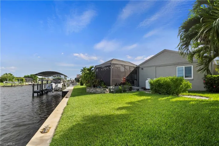 View of dock with a yard, glass enclosure, and a water view
