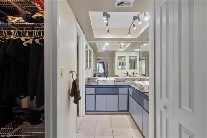 Bathroom featuring a tray ceiling, tile flooring, and vanity with extensive cabinet space