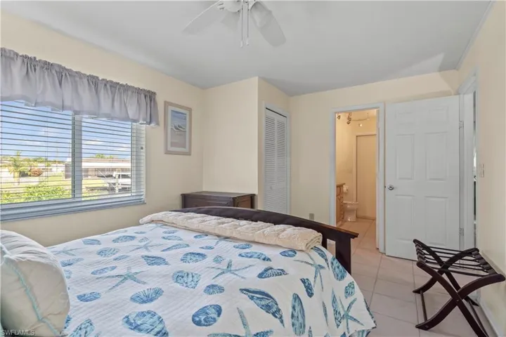 Tiled bedroom featuring a closet, ceiling fan, and ensuite bath