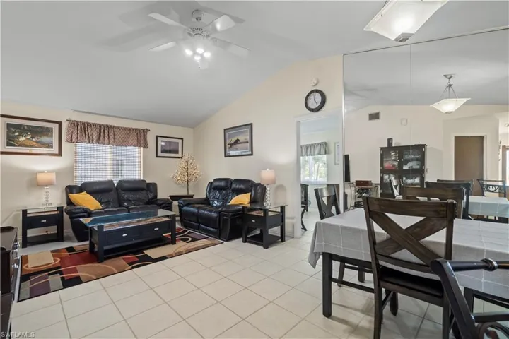 Living room featuring high vaulted ceiling, ceiling fan, and light tile floors