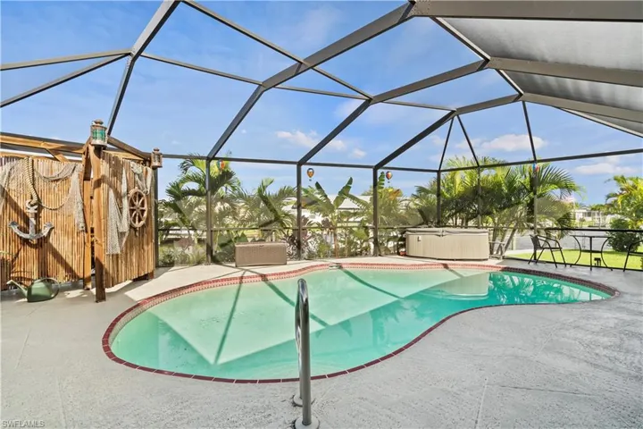 View of pool with a hot tub, a patio, and glass enclosure