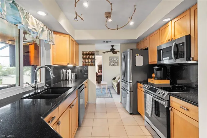 Kitchen with backsplash, stainless steel appliances, ceiling fan, track lighting, and sink
