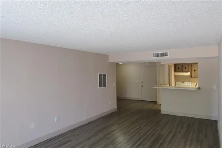 Empty room with a textured ceiling and dark hardwood / wood-style floors