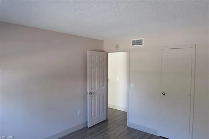 Unfurnished bedroom featuring dark wood-type flooring, a closet, and a textured ceiling