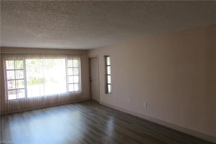 Empty room featuring dark hardwood / wood-style flooring and a textured ceiling