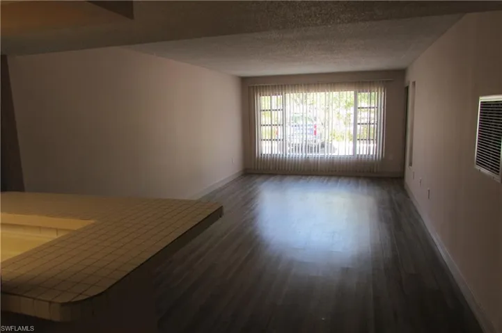 Empty room featuring a textured ceiling and dark hardwood / wood-style flooring