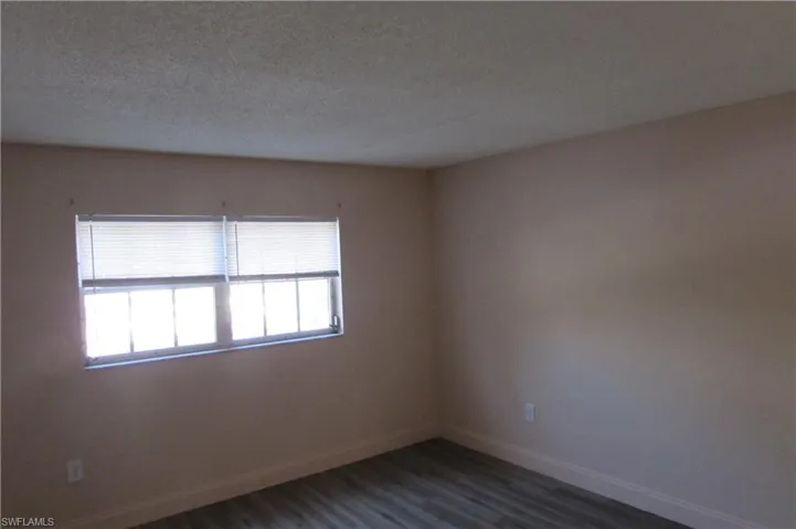 Spare room featuring a textured ceiling and dark hardwood / wood-style floors