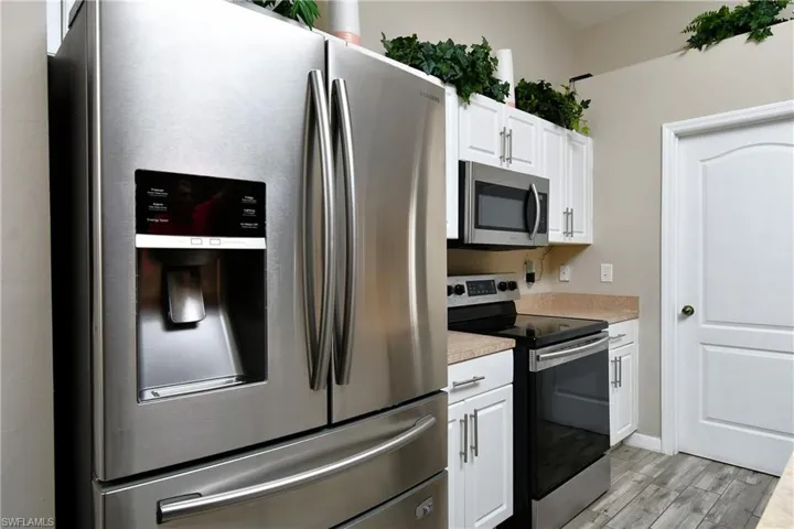 Kitchen featuring appliances with stainless steel finishes, white cabinets, light countertops, and light wood-style flooring