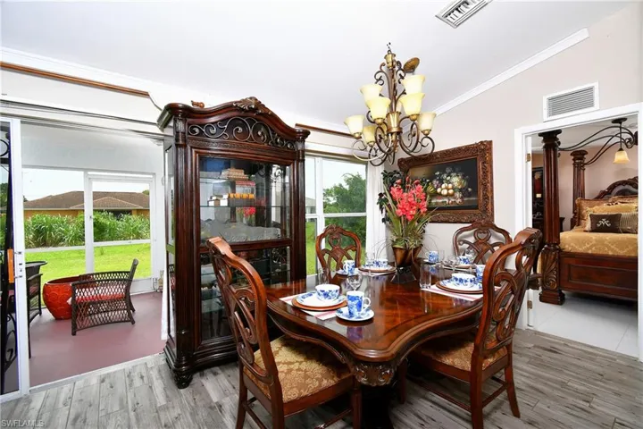 Dining room featuring a chandelier, ornamental molding, wood finished floors, and healthy amount of natural light