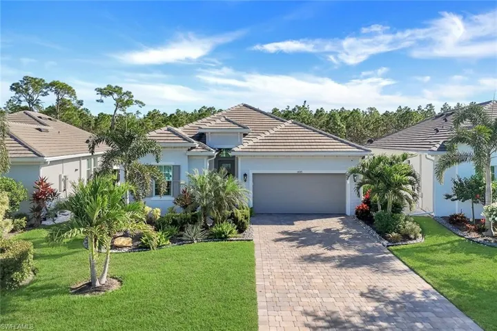 Lovely curb appeal featuring manicured landscaping and a paver driveway.