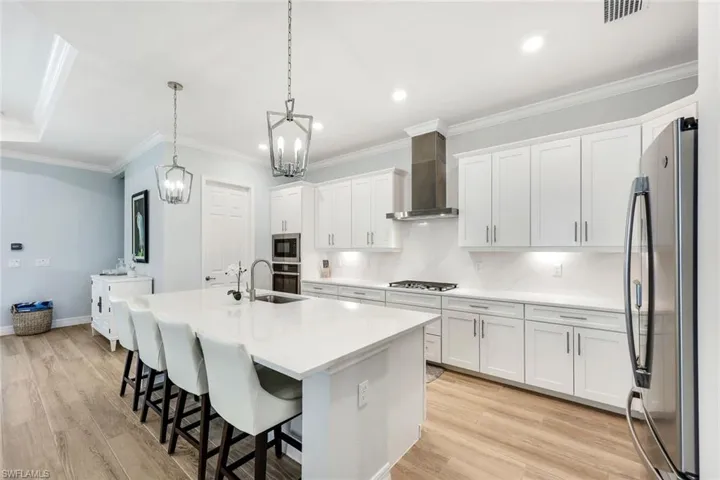 Bright, well-appointed kitchen featuring ample cabinetry, quartz countertops, new stainless appliances and custom lighting.