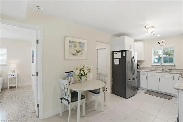 Kitchen with healthy amount of natural light, stainless steel appliances, white cabinetry, and light stone countertops - Virtually Edited Image