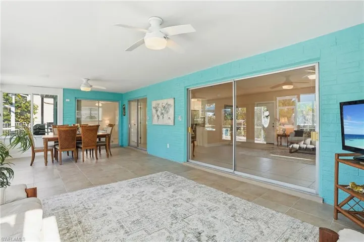 Sunroom with outdoor dining area, a ceiling fan, and plenty of natural light - Virtually Edited Image