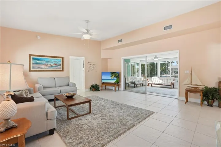 Living area with a ceiling fan, light tile patterned floors, and a high ceiling - Virtually Edited Image
