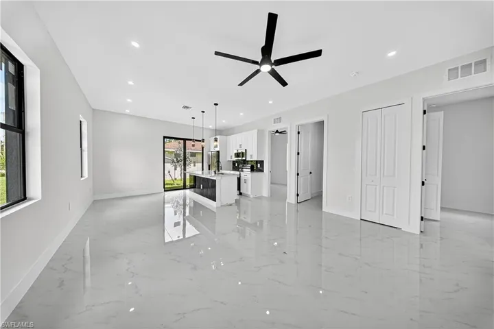 Unfurnished living room with light marble finish flooring, recessed lighting, and ceiling fan