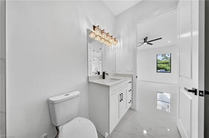 Bathroom featuring light marble finish flooring, vanity, and ceiling fan