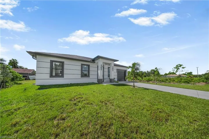 View of front of home featuring concrete driveway, a front yard, a garage, and stucco siding