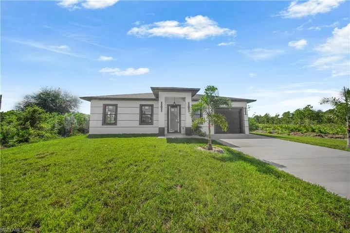 Prairie-style home featuring driveway, a front yard, and a garage