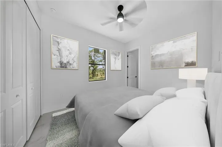 Bedroom with a closet, ceiling fan, and marble finish floors