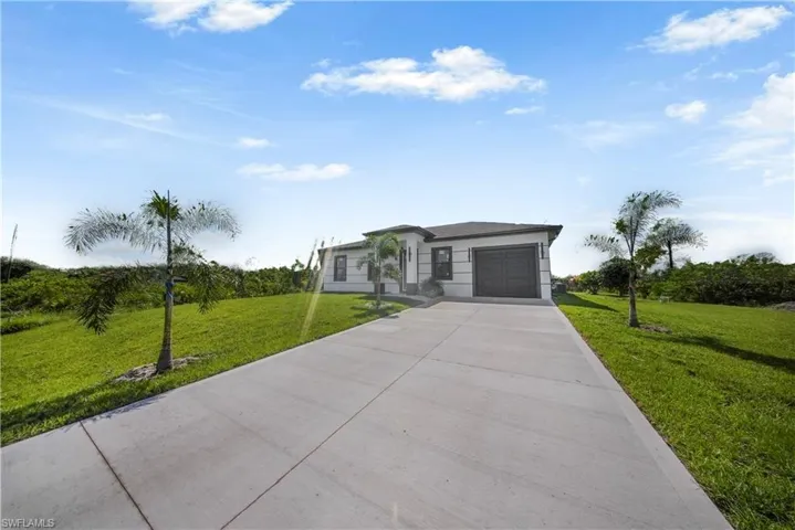 Prairie-style house with concrete driveway, a front lawn, and an attached garage