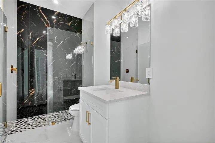 Full bathroom with vanity, a marble finish shower, and marble finish floors