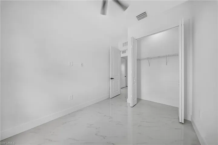 Unfurnished bedroom with light marble finish floors and a closet