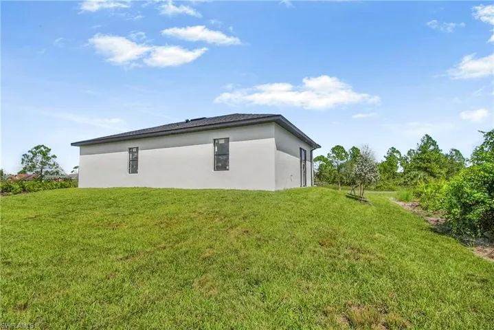 View of side of property featuring a yard and stucco siding