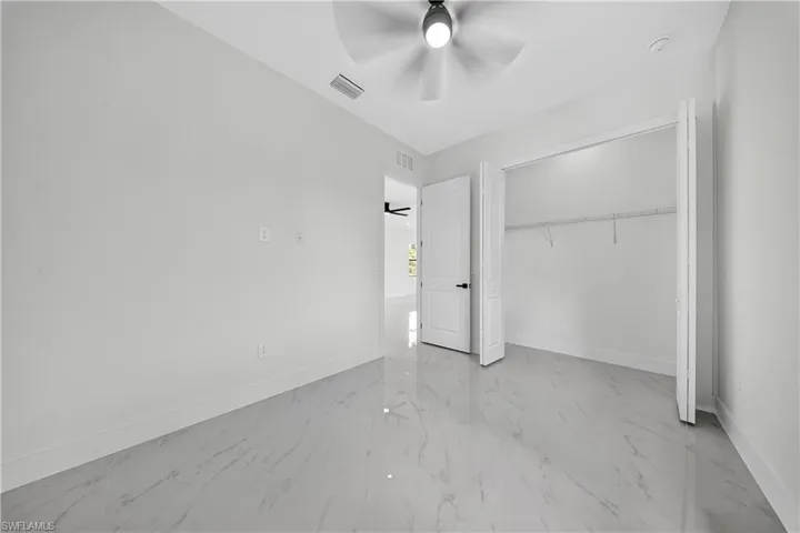 Unfurnished bedroom featuring light marble finish floors, a ceiling fan, and a closet