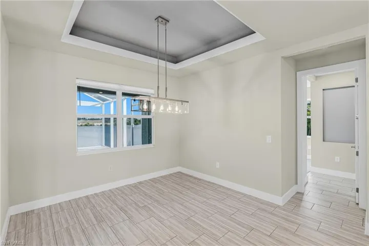 Empty room featuring a raised ceiling, a water view, and wood tiled floors