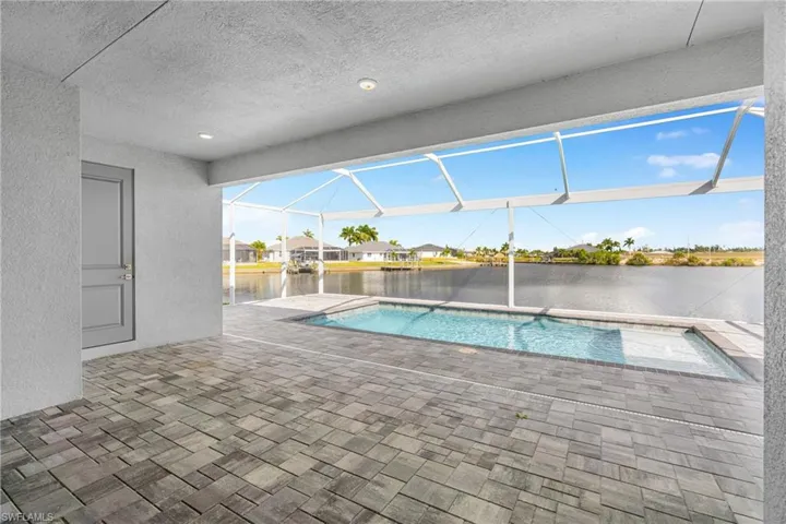 Swimming pool featuring a patio area, a sunroom, glass enclosure, a water view, and a residential view
