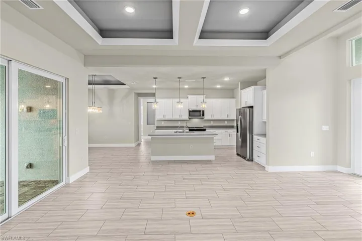 Kitchen with white cabinets, decorative light fixtures, recessed lighting, appliances with stainless steel finishes, and open floor plan