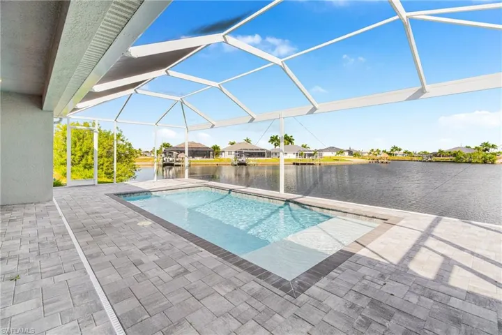 Swimming pool with a sunroom, a water view, a lanai, and a patio