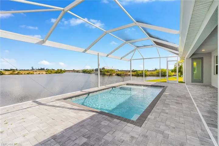 Outdoor pool featuring a sunroom, a lanai, a patio area, and a water view