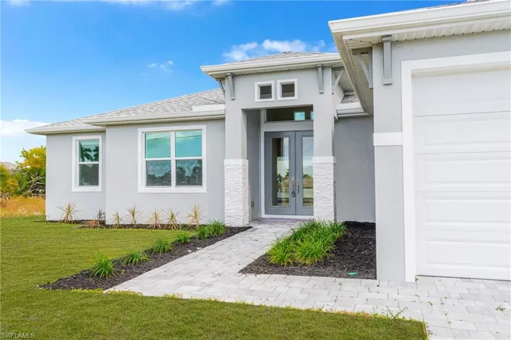 View of exterior entry with stucco siding, french doors, a garage, and a shingled roof