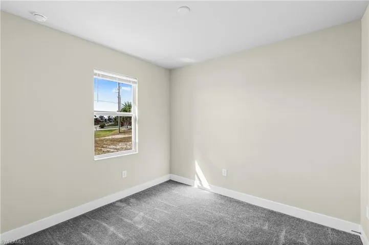 Carpeted spare room featuring baseboards
