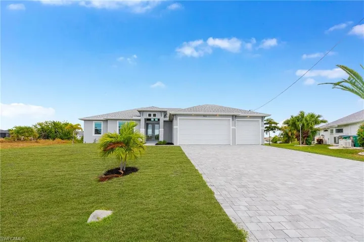 Prairie-style home featuring a front lawn, a garage, decorative driveway, and stucco siding